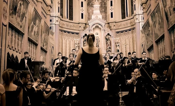 Marianna Ruggiero de costas conduzindo a orquestra da Maison Musique
