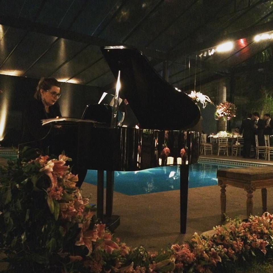 Piano de cauda em apresentação instrumental ao lado de uma piscina